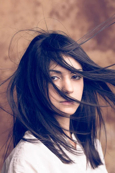 Rüzgarda savrulan uzun saçlı güzel siyah saçlı kızın portresi. Güzel, koyu saçlı, uzun saçlı, rüzgarda uçuşan bir kızın kaliteli portresi.