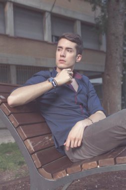 Güzel siyah saçlı çocuk Milan parkında bir bankta otururken poz veriyor. Yüksek kalite fotoğraf