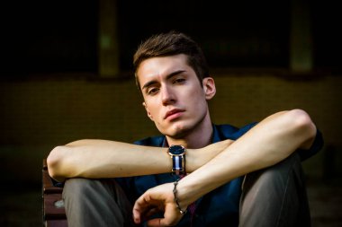 Güzel siyah saçlı çocuk Milan parkında bir bankta otururken poz veriyor. Yüksek kalite fotoğraf