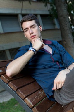 Güzel siyah saçlı çocuk Milan parkında bir bankta otururken poz veriyor. Yüksek kalite fotoğraf