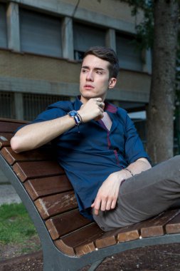 Güzel siyah saçlı çocuk Milan parkında bir bankta otururken poz veriyor. Yüksek kalite fotoğraf