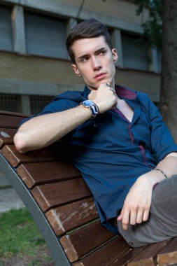 Güzel siyah saçlı çocuk Milan parkında bir bankta otururken poz veriyor. Yüksek kalite fotoğraf