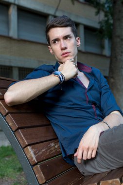 Güzel siyah saçlı çocuk Milan parkında bir bankta otururken poz veriyor. Yüksek kalite fotoğraf