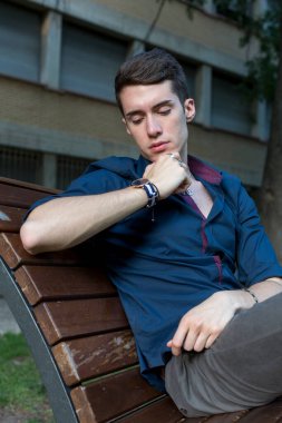 Güzel siyah saçlı çocuk Milan parkında bir bankta otururken poz veriyor. Yüksek kalite fotoğraf