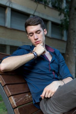 Güzel siyah saçlı çocuk Milan parkında bir bankta otururken poz veriyor. Yüksek kalite fotoğraf