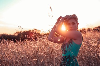 Gün batımında buğday tarlasında ilahi elbiseli güzel sarışın kız. Yüksek kalite fotoğraf