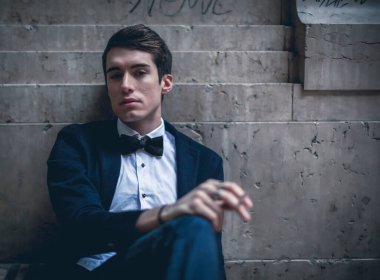 Güzel, şık giyimli bir adam şehir merkezinde sigara içiyor. Yüksek kalite fotoğraf