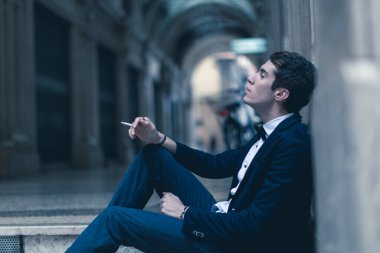 beautiful elegant dressed man smokes in city center. High quality photo clipart