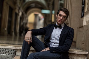 Güzel, şık giyimli bir adam şehir merkezinde sigara içiyor. Yüksek kalite fotoğraf