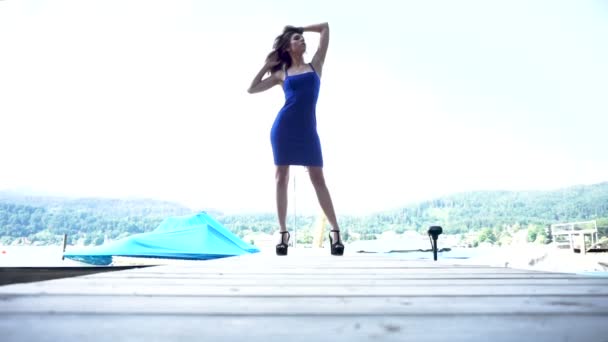 Hermosa chica morena con el pelo largo posando en barce muelle con azul sexy vestido corto y tacones — Vídeos de Stock