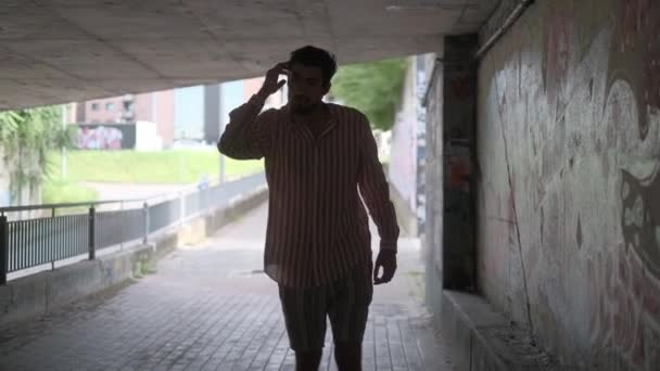Schöner Junge mit gestreiftem Hemd und Bermuda-Shorts in einer Unterführung — Stockvideo