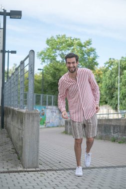 Şehir merkezinde kısa pantolonlu ve çizgili gömlekli güzel siyah saçlı bir çocuk var. Yüksek kalite fotoğraf