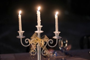 Üç dallı şamdan, masa ve siyah arka planda beyaz mumlarla aydınlatılmış. Yüksek kalite fotoğraf