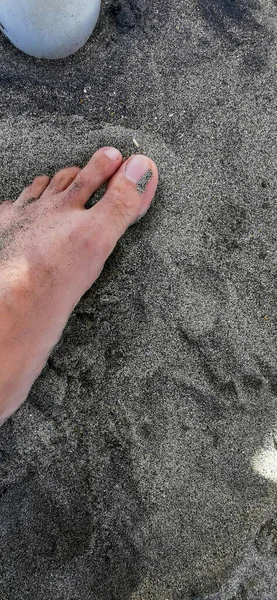 male foot on black sand in the Roman lido of porpoises ostia lido. High quality photo