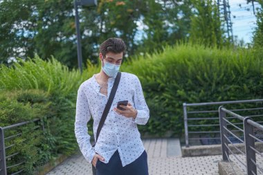 Güzel bir genç adam 19 ameliyat maskesiyle şehirde dolaşıyor. Yüksek kalite fotoğraf