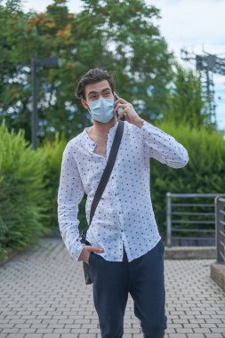 Güzel bir genç adam 19 ameliyat maskesiyle şehirde dolaşıyor. Yüksek kalite fotoğraf