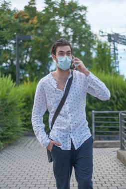 Güzel bir genç adam 19 ameliyat maskesiyle şehirde dolaşıyor. Yüksek kalite fotoğraf