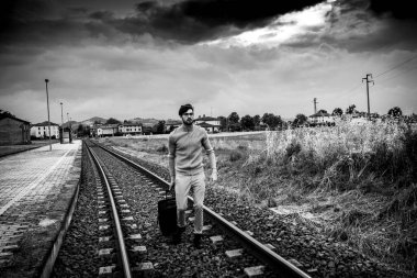 Delikanlı trenin raylarında trolly bavuluyla yürüyor. Yüksek kalite fotoğraf