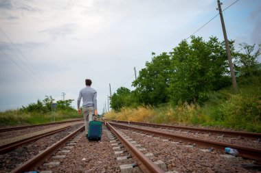 Delikanlı trenin raylarında trolly bavuluyla yürüyor. Yüksek kalite fotoğraf