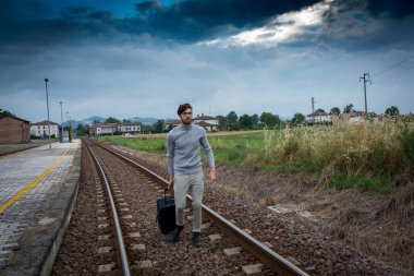 Delikanlı trenin raylarında trolly bavuluyla yürüyor. Yüksek kalite fotoğraf