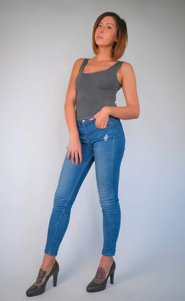 beautiful brunette girl with short hair gray top and jeans and high heels posing. High quality photo