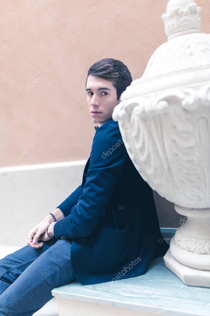 beautiful dark-haired boy poses in the center of reggio emilia with elegant shirt and pappillon jacket