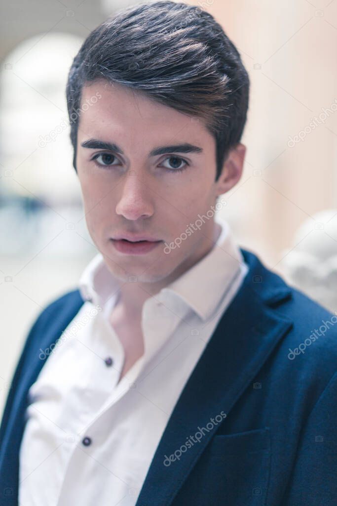 beautiful dark-haired boy poses in the center of reggio emilia with elegant shirt and pappillon jacket