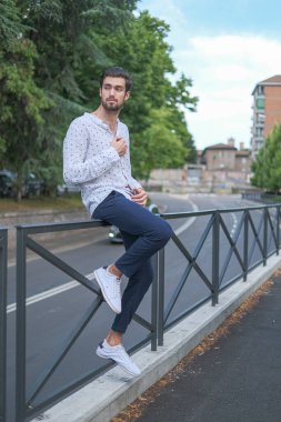 Beyaz çocuk şehir merkezinde bir tırabzanda oturuyor. Yüksek kalite fotoğraf