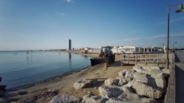 Buldozer, Cesenatico sahilinde şafak vakti algleri temizlemek için çalışır. Yüksek kalite 4k görüntü
