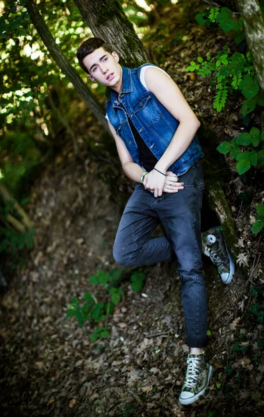 森の中でジーンジャケットを着て屋外でポーズをとる美しい男 — ストック写真