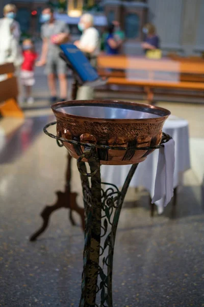 baptismal font in catholic church in italy for baptism in copper on pedestal. High quality photo