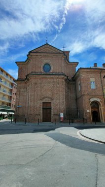 İtalya 'nın Bra kentindeki Sant' Andrea kilisesinin uzun, tarihi tuğla çan kulesinin çarpıcı manzarası güneşli bir günde kasaba meydanının üzerinde görkemli bir şekilde duruyor. Yüksek kalite fotoğraf