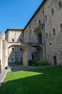 Ozan Kalesi 'nin iç avlusu, İtalya' nın Aosta Vadisi 'ndeki bir ortaçağ kalesi, taş mimarisi, köprüsü ve parlak mavi gökyüzünün altındaki yeşil çimenliği ile. Yüksek kalite fotoğraf