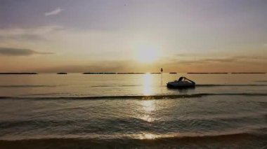 Güneş batarken sakin Adriyatik Denizi 'nde kürek çeken bir insanın huzurlu ve manzaralı görüntüsü suya güzel bir altın yansıma yansıtıyor. Riviera Romagnola Cesenatico Rini 'de. Yüksek kalite