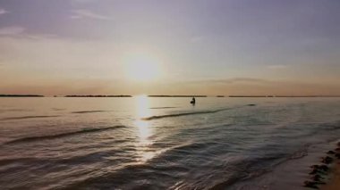 Güneş batarken sakin Adriyatik Denizi 'nde kürek çeken bir insanın huzurlu ve manzaralı görüntüsü suya güzel bir altın yansıma yansıtıyor. Riviera Romagnola Cesenatico Rini 'de. Yüksek kalite