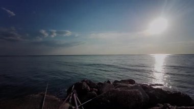 Sabah güneşi, İtalya 'nın Cesenatico kentindeki sakin Adriyatik Denizi üzerinde yükseliyor. Işık, güzel bir yaz sabahında kayalık bir dalgakırandan görülen sakin suyu yansıtır. Yüksek kalite 4k görüntü