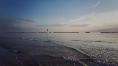 Güneş batarken sakin Adriyatik Denizi 'nde kürek çeken bir insanın huzurlu ve manzaralı görüntüsü suya güzel bir altın yansıma yansıtıyor. Riviera Romagnola Cesenatico Rini 'de. Yüksek kalite 4k görüntü