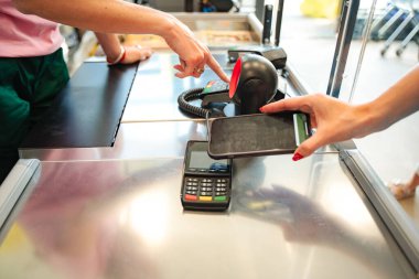 Markette akıllı telefon kullanarak bakkaliyenin parasını ödeyen müşteri, veznedarın da yardımıyla...