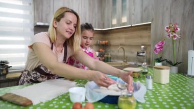 Mother and daughter making a pie together in the kitchen