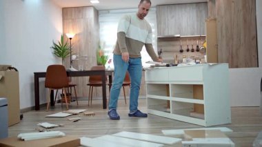 Man assembling a white piece of furniture in his new modern apartment