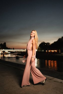 Güneş batarken zarif bir kadın huzurlu bir nehrin kenarında yürür ve büyülü bir atmosfer yaratır..