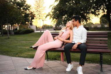 Bir çift parkta sakin bir anın tadını çıkarıyor, altın güneş ışığı sıcak bir atmosfer yaratıyor..