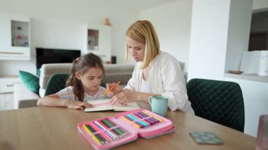 Mother helping daughter drawing straight lines with ruler and pencil