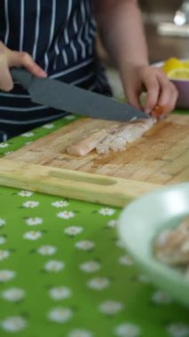 Chef slicing fresh fish fillet on wooden cutting board