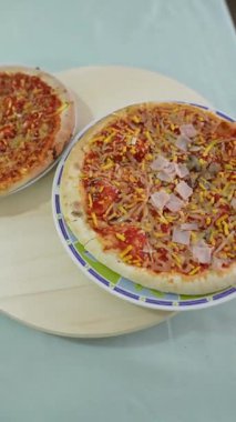 Two pizzas rotating on a wooden tray