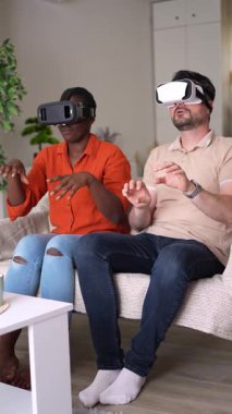 Multiethnic couple wearing virtual reality headsets and enjoying interactive experience