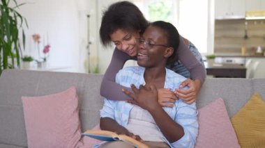 Mother and daughter sharing a tender moment while reading a book, embracing each other with love and affection