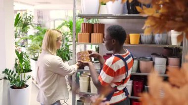 Florist showing a flowerpot to a customer in a plant shop footage