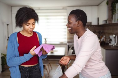 Mother teaching her daughter how to iron clothes at home photo