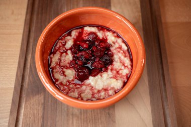 Lezzetli yulaf ezmesi, zengin bir böğürtlen kompostosu ile kaplanmış ve ahşap bir yüzeye yerleştirilip rahatlatıcı bir kahvaltı havası yaratıyor..